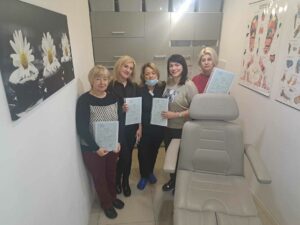 Grupa z certyfikatami w pracowni kosmetycznej.