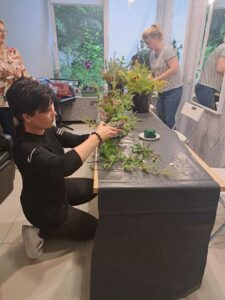 Uczestniczki przygotowują elementy roślinne do dekoracji.